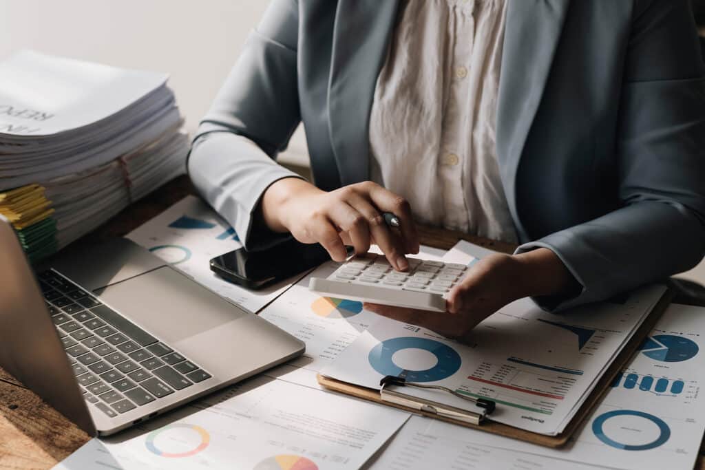 Business Woman Using Calculator To Calculate Financial Report, W